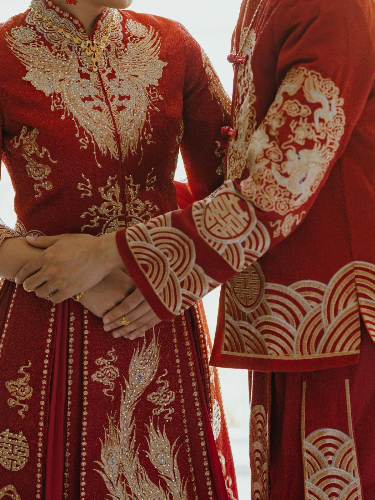新人身穿紅金刺繡秀禾服，雙手交握